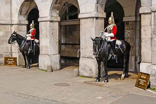 The mounted guard at Horseguards parade, Whitehall, London, England, UK, The guards are on horseback and in ceremonial outfits but are all serving soldiers in the British army. There are tourists looking at the horse and rider.