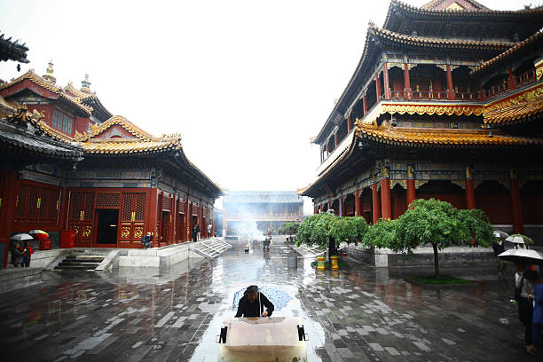 Beijing, China - September 23, 2014: A woman burns incense at the Lama Temple in Beijing, China, on a rainy day.
