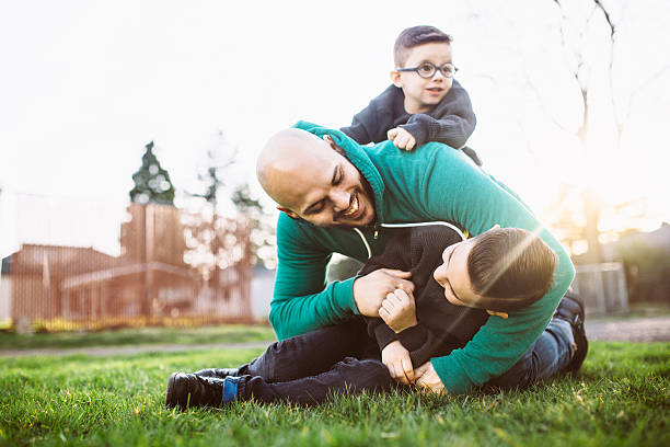 padre con sus niños jugando en el exterior - jugar a luchar fotografías e imágenes de stock
