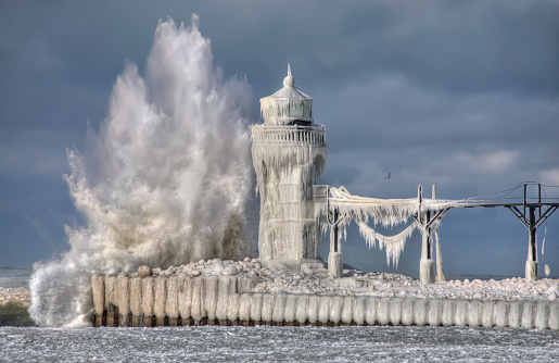 A mighty wave crashes into a frozen lighthouse off the coast of Michigan.