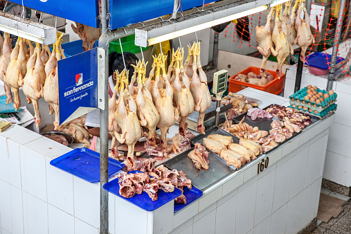 Lima, Peru - January 9, 2015: Prepared chickens hanging up in Lima street market. Two women are pictured at work on the stall