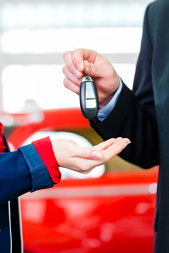 Woman with key to new auto in car dealership