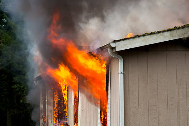 Flames erupting from window in burning home stock photo