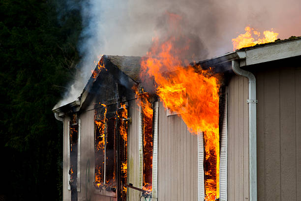 Flames erupting from window in burning home stock photo