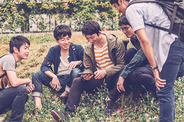 Five male japanese students talking, having fun in the campus park, Kyoto, Japan, Asia. They are looking at a digital tablet. Copy space. Nikon D800, full frame, XXXL. iStockalypse Kyoto 2016.