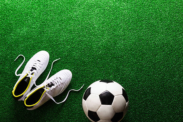 istock Soccer ball and cleats against green artificial turf, studio sho 538778496