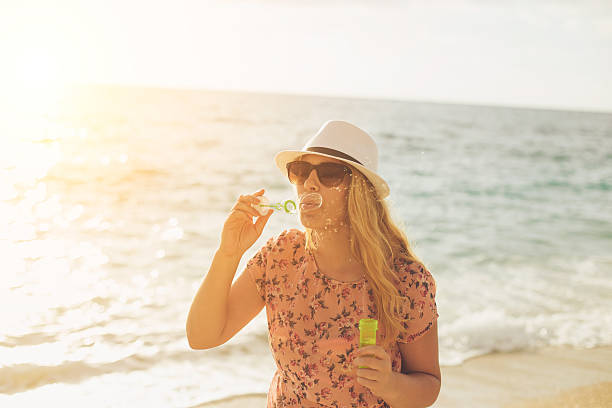 istock Young woman playfully blowing soap bubbles 538778574