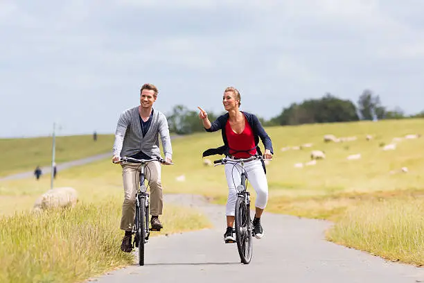 Couple having bicycle tour with bike at levee with sheep