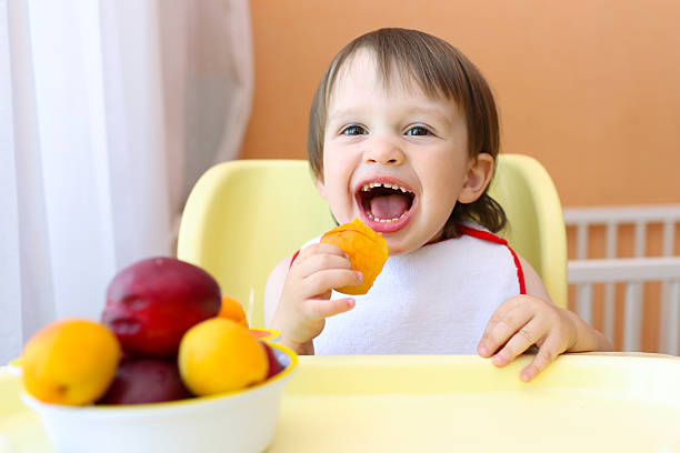 istock smiling baby eating fruits 538779381