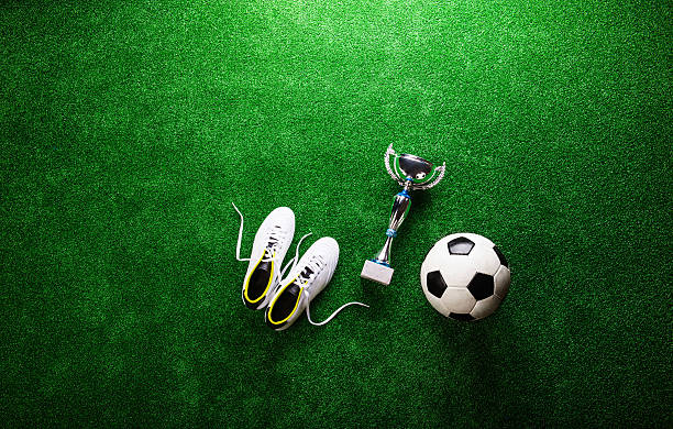 istock Soccer ball, cleats and trophy against green artificial turf 538779518