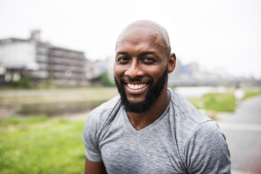 An African American adult man working out in nature and smiling