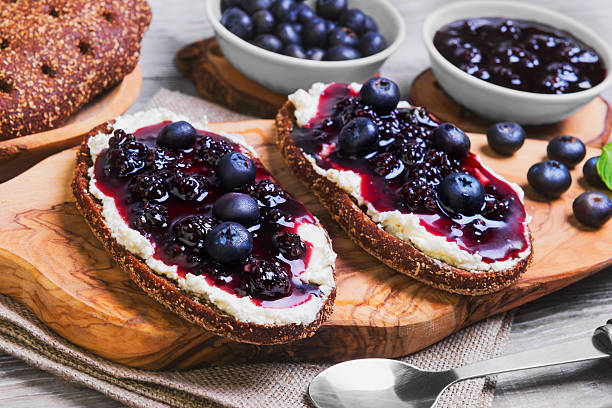 Sweet berry crostini sandwiches Sweet berry crostini sandwiches with blackberry jam and berries blueberries, whole grain bread for sandwiches, sandwiches board, spoon, mint leaves on a bright white background wooden crostini stock pictures, royalty-free photos & images