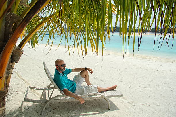 istock bald  men on a sun lounger under a palm in beach 538783950