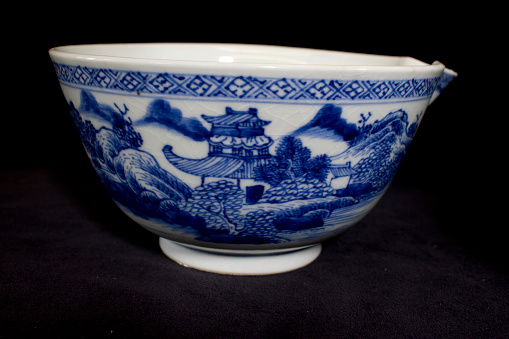 Horizontal extreme closeup photo of the blue leaves and rose flower pattern decorating a French antique ceramic covered soup tureen in a dining room. Provence, south of France.