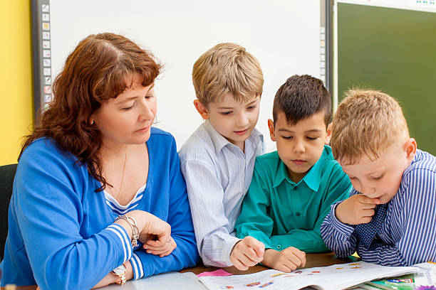 istock The teacher reads a book with three pupils 538793006