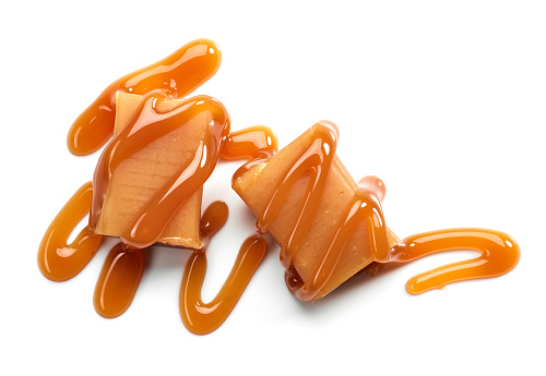 caramel candies and sweet sauce isolated on white background, top view