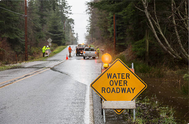 Emergency workers placing warning signs on flooded road Emergency response after a natural disaster: emergency workers placing warning signs on flooded road truck in rain stock pictures, royalty-free photos & images