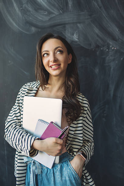 istock Young beautiful woman with laptop and notes in hands smiling 538798498