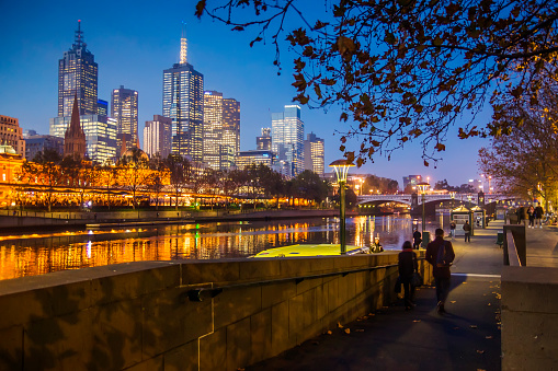 Melbourne, Australia - June 2, 2016: People around the southern riverbank of the Yarra River at dusk, with skyscrapers in the Melbourne CBD visible on the opposite.