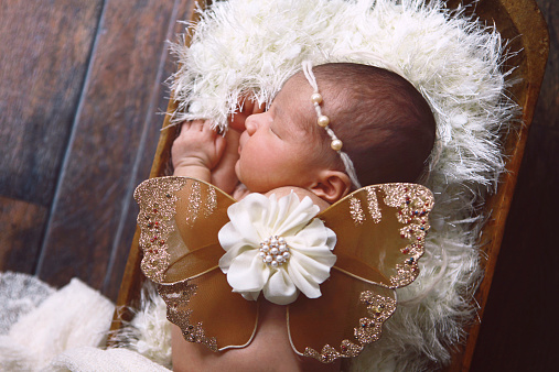 A beautiful newborn baby girl wearing butterfly wings.
