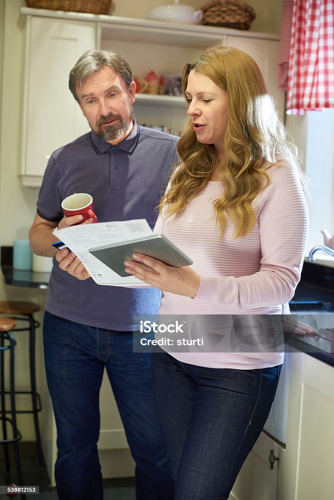 mature couple looking online mature couple at home using their digital tablet to feel somehow validated by a consumer driven society 2015 Stock Photo