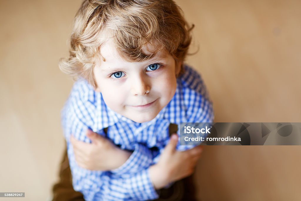 Portrait of adorable little boy with blue eyes Portrait of adorable little boy with blond hairs and blue eyes, indoor. 'at' Symbol Stock Photo