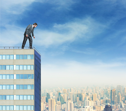 Businessman looks down from a high building against the city