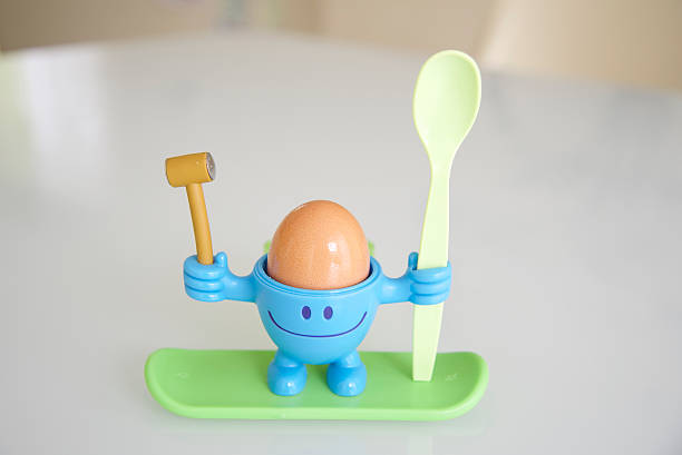 tenant un œuf à la coque pour le petit déjeuner - place setting spoon silverware kitchen utensil photos et images de collection