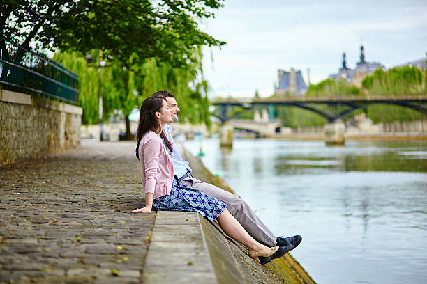 The City of Paris France on October 19, 2023:   A couple in discussion while sitting along the bank of the Seine River in Paris France at night