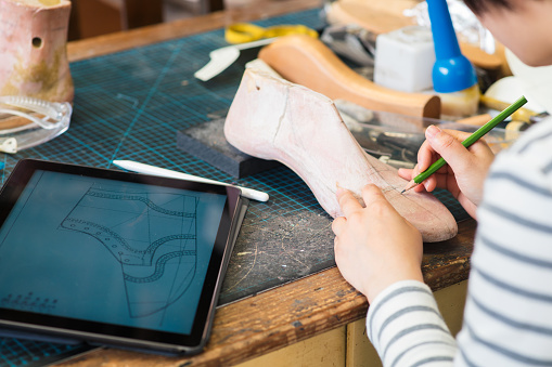 Over the shoulder view of a shoe maker as she draws the design of a new shoe. Kyoto, Japan. May 2016