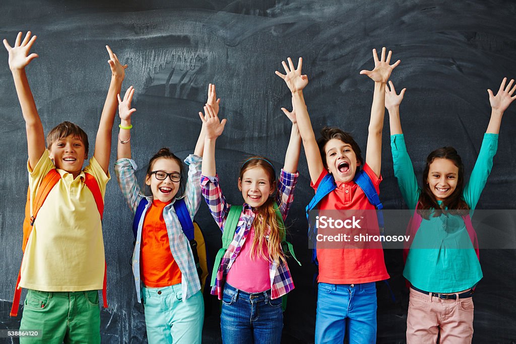 Happy schoolchildren Excited schoolchildren standing with hands up Child Stock Photo