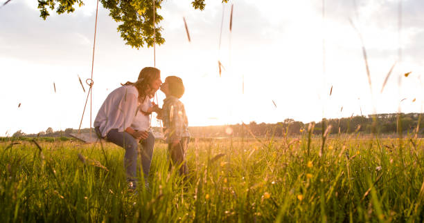 istock Mother swinging while kissing son on field 538866722