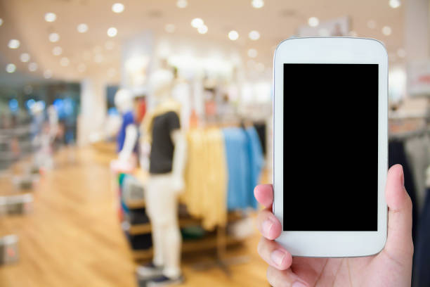 istock hand hold mobile phone with clothing store background 538869358