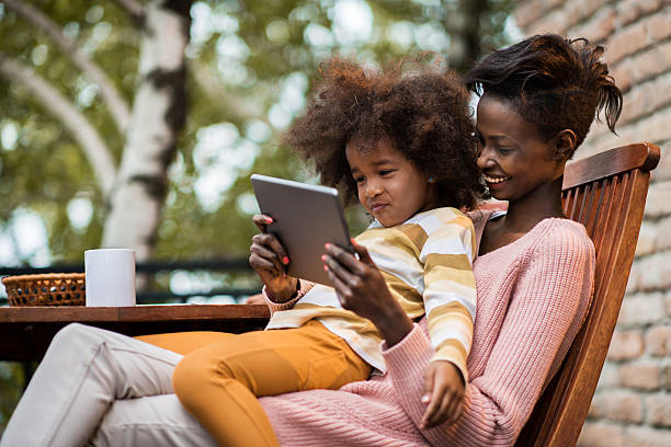istock African American mother and daughter using digital tablet on terrace. 538871440