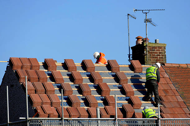 Roofing. Sutton-in-Ashfield, Nottinghamshire, UK. February 19, 2016.  A group of workmen covering a roof of a semi-detached house with tile slates, taking care to stand on the lats as they dice with danger.  nottinghamshire stock pictures, royalty-free photos & images