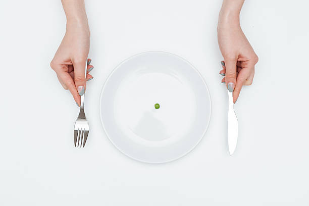 istock Woman eating one small green pea using knife and fork 538873056