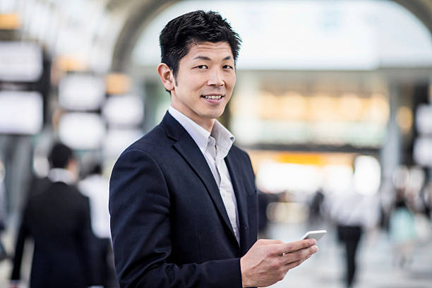 retrato de homem de negócios japoneses a olhar para o seu telefone no posto de trabalho - rush hour commuter on the phone tokyo prefecture imagens e fotografias de stock