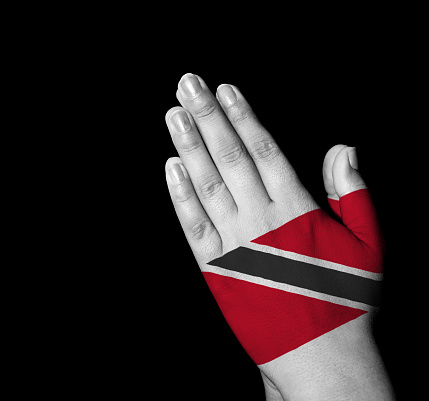 Hands folded in prayer - Trinidad and Tobago flag painted on hands - Digitally generated
