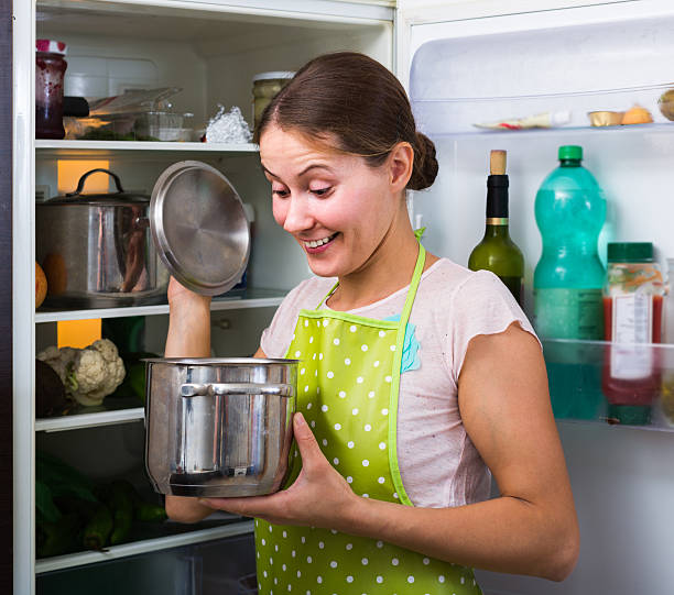 istock brunette in apron looking at products in refrigerator 538876540