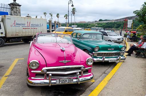 Havana, Cuba - December 10, 2015: American classic cars and their owners waiting for hire by tourists in Old Havana.