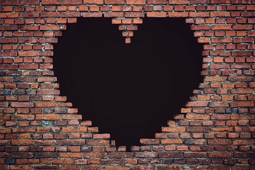 - A brick wall with a black hole - form of a heart shape.