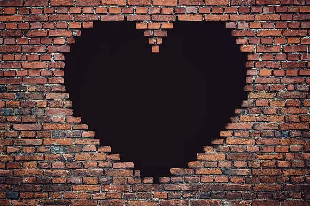- A brick wall with a black hole - form of a heart shape.