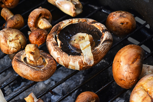 Brown champignons portobello mushrooms being cooked on char grill