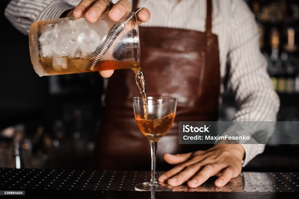 barman pouring alcoholic cocktail in glass barman making and pouring alcoholic cocktail at the bar Alcohol - Drink Stock Photo