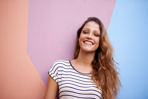 Portrait of a young woman standing against a colorful wall