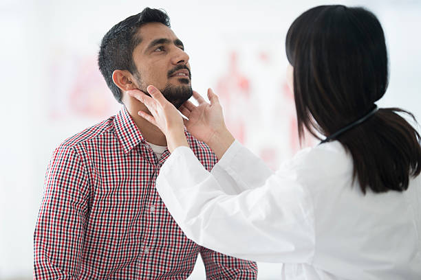 Checking the Size of a Man's Lymph Nodes A man is going to the doctors office for a check up about his soar throat. The doctor is asking him medical questions. lymph node photos stock pictures, royalty-free photos & images