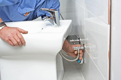 Construction worker installing a bidet in a bathroom.