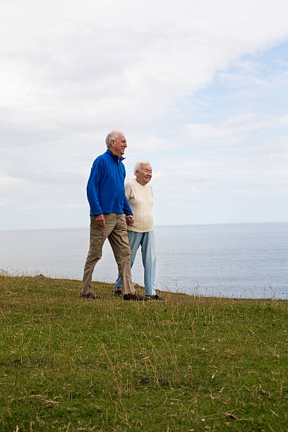 Happy caucasian senior couple smile and enjoy the travel with backpack in the outdoor nature forest - alternative free vacation concept for aged people - joyful lifestyle and hug and love
