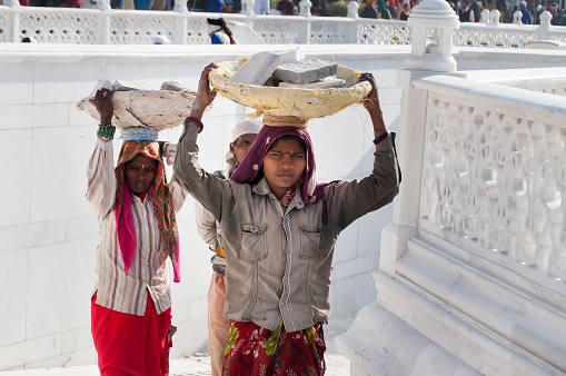 Amritsar, India - December 7, 2014:  Unidentified women carry basket of stones on their head at Golden Temple (Harmandir Sahib also Darbar Sahib). Golden Temple is the holiest Sikh gurdwara located in the city of Amritsar, Punjab, India.