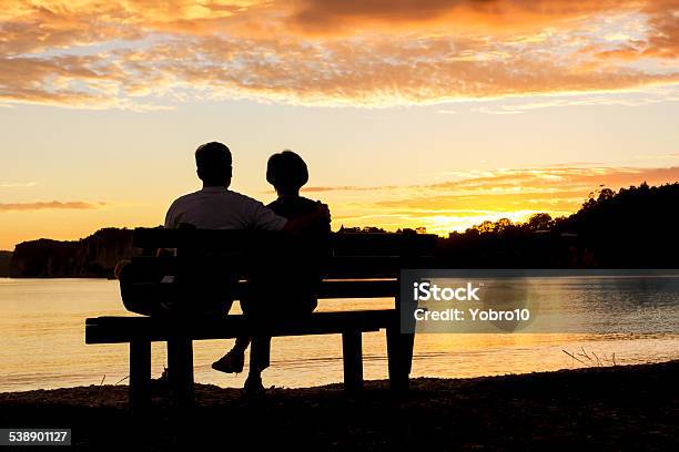 Couple Watching A Beautiful Sunset Together Stock Photo - Download Image Now - Couple - Relationship, Bench, Sunset